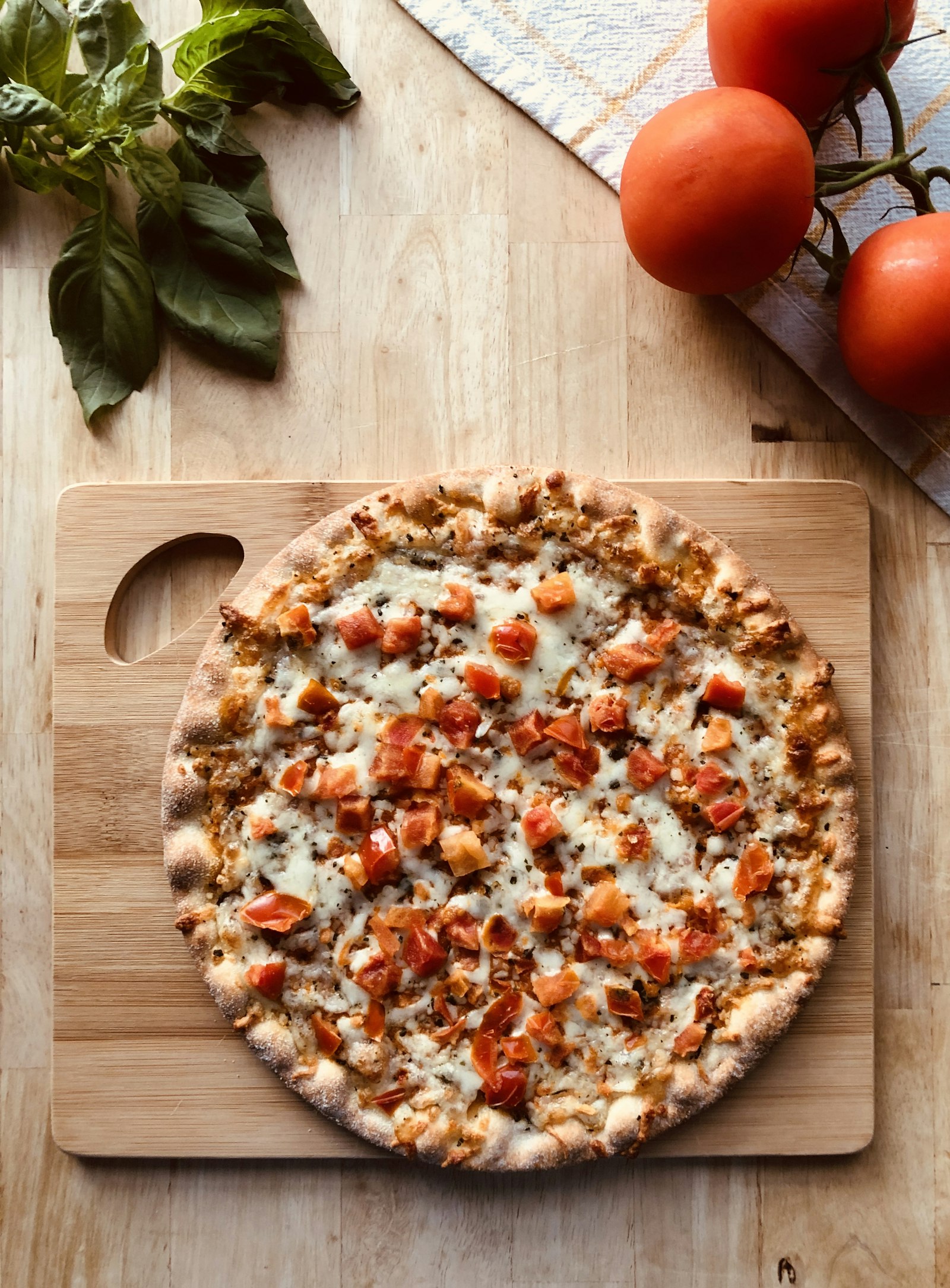 Pizza a la piedra con albahaca sobre tabla de madera